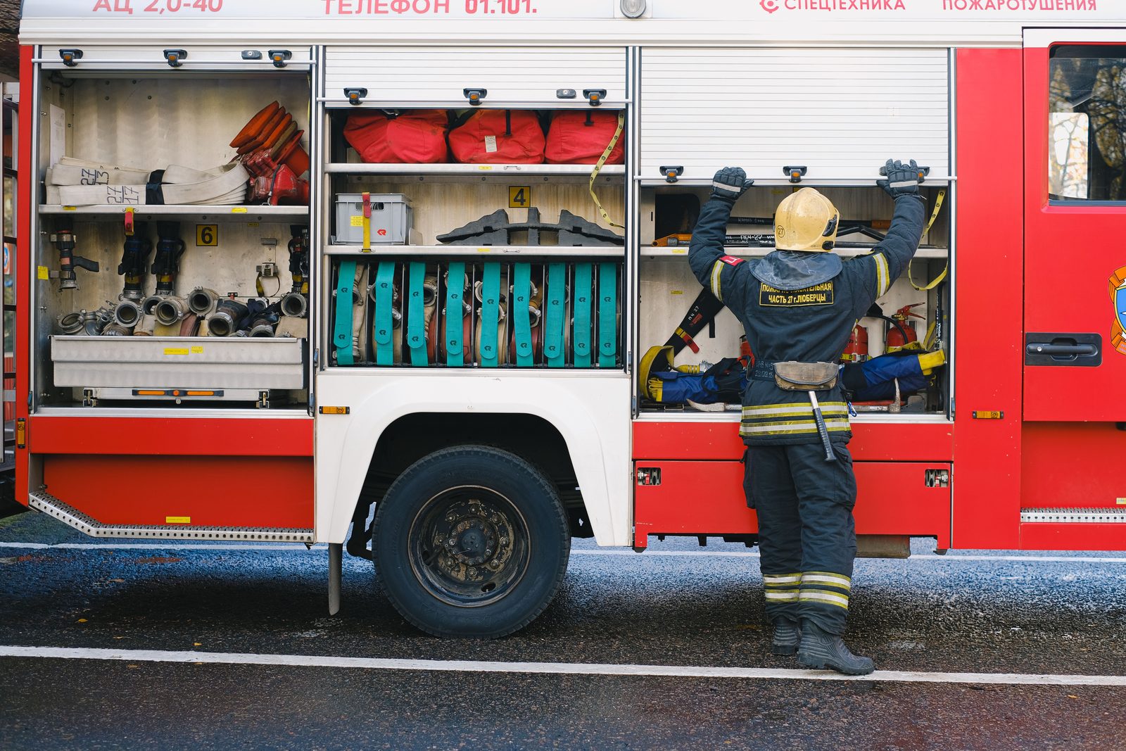 Firefighter checking equipment compartments on a fire apparatus